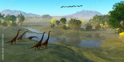 Giraffatitan Dinosaur Valley - A flock of Archaeopteryx birds fly over a herd of Giraffatitan dinosaurs as they reach a river to drink. photo