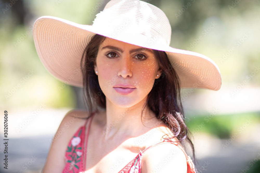 Portrait of a beautiful young Italian woman wearing a straw hat in sunny warm weather day.