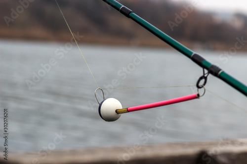 spinning bite indicator, a nod on a fishing rod by the river © Nikolay