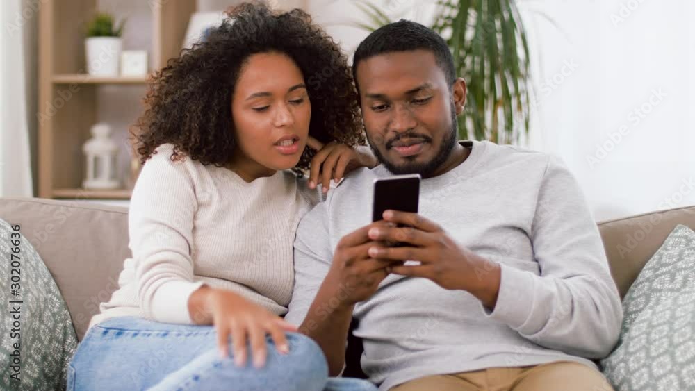 technology, internet and people concept - happy african american couple with smartphone at home technology, internet and people concept - happy african american couple with smartphone at home