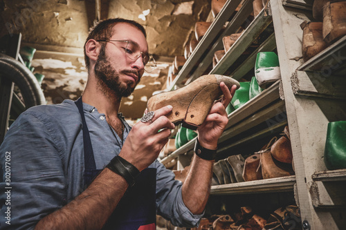 Bearded cobbler in glasses found the right shoe form for his new collection.