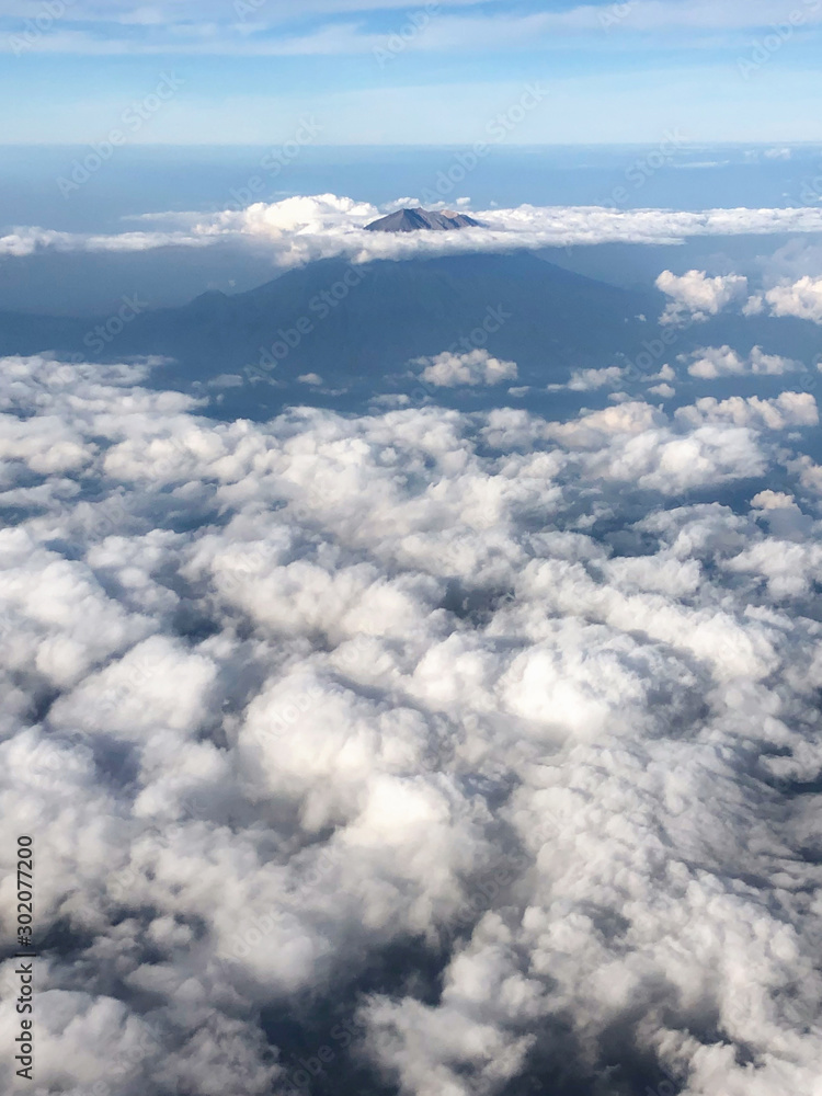 Aerial view of Agung volcano peak in Bali from plane window. Cloudy beautiful weather. Aerial view of Agung volcano peak in Bali from plane window. Cloudy beautiful weather.