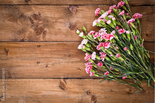 Carnation with pink and white petals on a wooden table. A bouquet of flowers as a gift. Vintage photo. Free space for text.