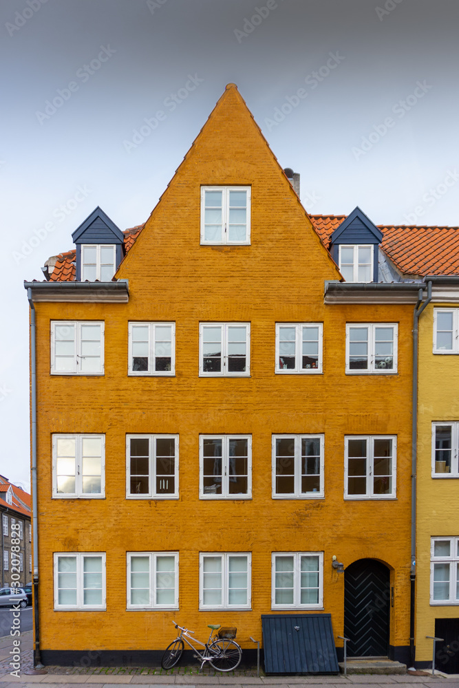 Copenhagen’s ochre painted old building. Front facade view with a parked bicycle. Charming Street Scene. Vertical orientation. 