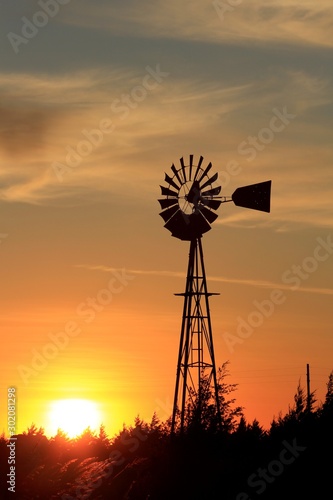 silhouette of windmill at sunset with colorful clouds west of Nickerson Kansas USA.