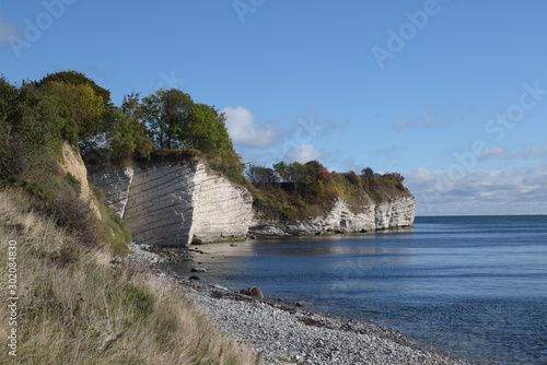 Stevns Klint, chalk cliff in the southeast of the Danish island Zealand in the Baltic Sea, a tourist attraction against a blue sky with copy space photo