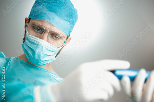 the assistant passes the instrument to the surgeon in the operating room.
