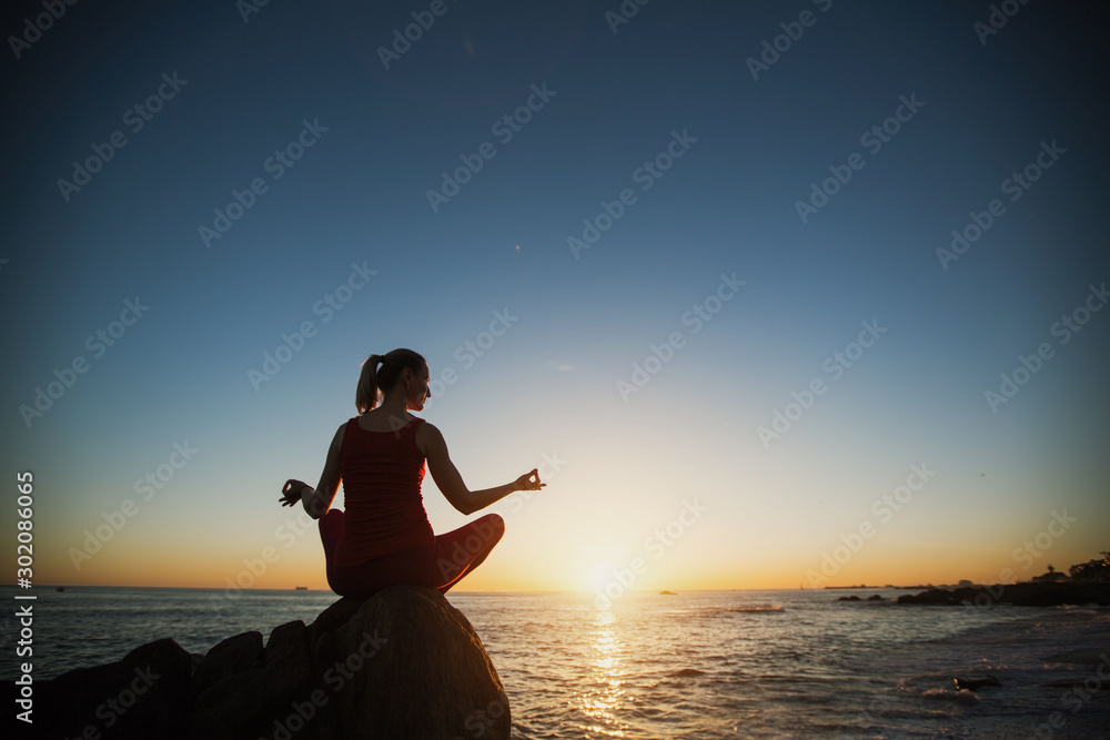 Yoga silhouette woman meditation near sea and sunset.