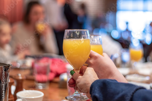 Enjoying mimosas at brunch - two hands clinking glasses