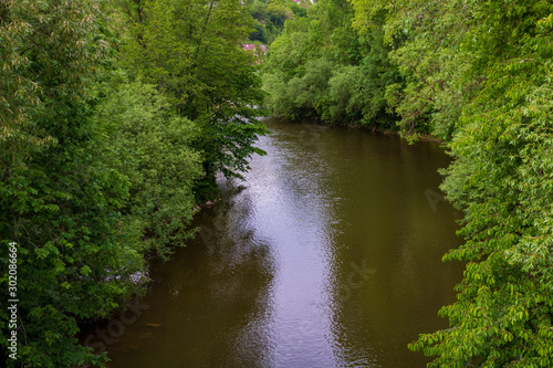 Flowing river  Jagst  between green trees in Neudenau  Germany