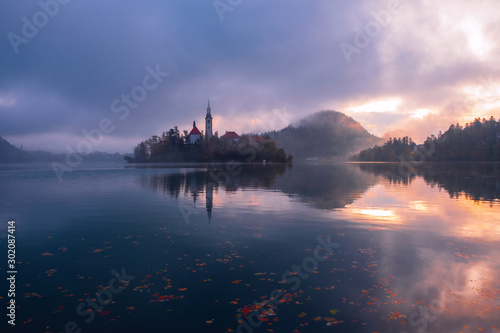 Famous Bled Lake in Triglav National Park in the Julian Alps with a forest in autumn colors at sunrise