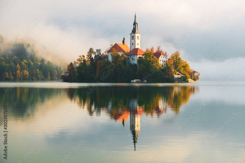Famous Bled Lake in Triglav National Park in the Julian Alps with a forest in autumn colors at sunrise