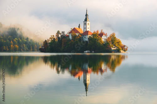Famous Bled Lake in Triglav National Park in the Julian Alps with a forest in autumn colors at sunrise