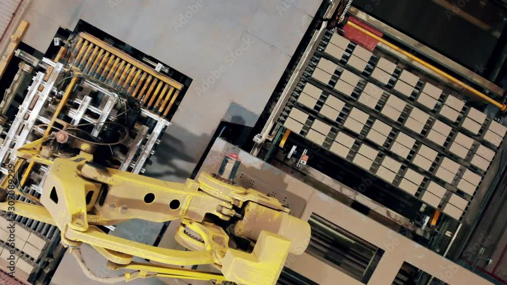 Robot manipulator worling at modern factory. Bricks are moving and getting mechanically relocated in a top view Robot manipulator worling at modern factory. Bricks are moving and getting mechanically relocated in a top view