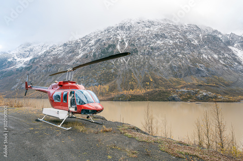 A red helicopter sits by an alpine mountain lake © scottshoots