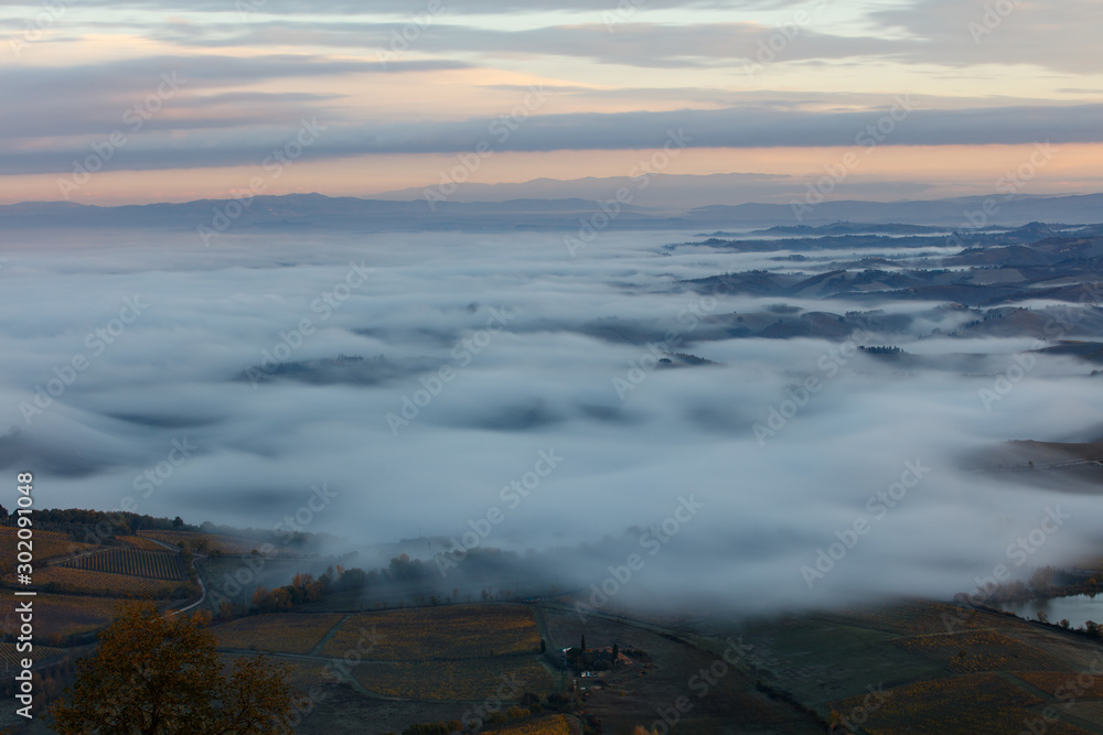 Fototapeta premium Tuscan landscape at sunrise under the fog