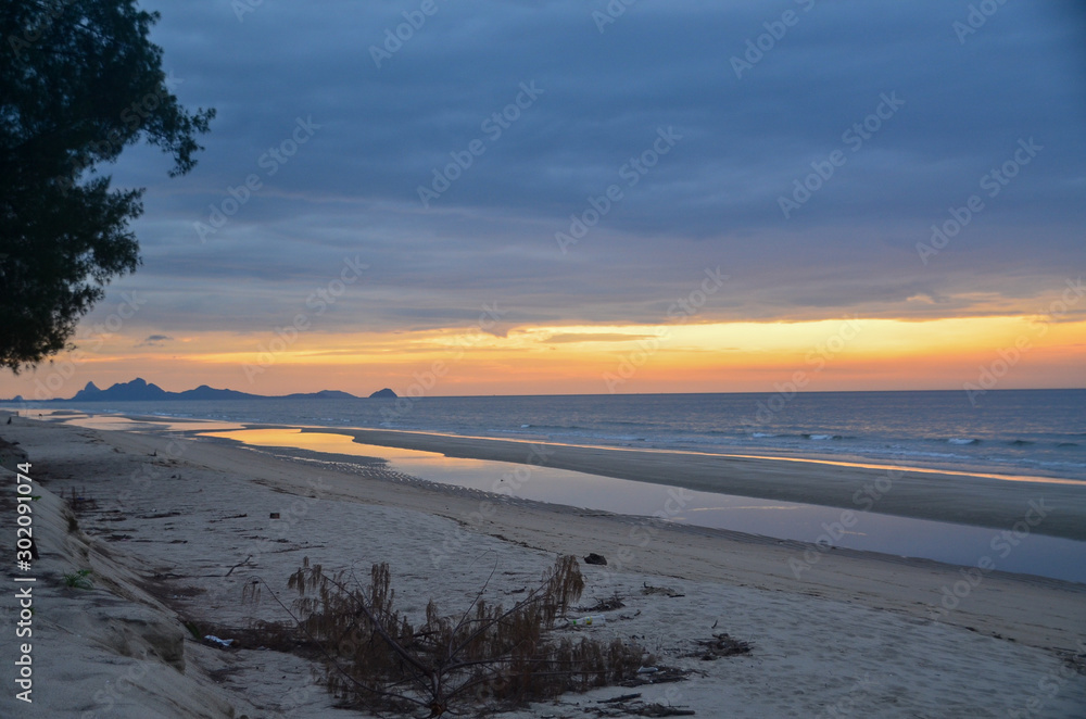 A stormy tropical orange and yellow coloured cloudy coastal sunrise seascape and beach. Thailand. A stormy tropical orange and yellow coloured cloudy coastal sunrise seascape and beach. Thailand.