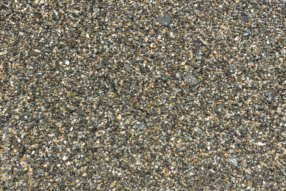 Small stone. Wet black sand. Pebble beach. Sand texture. Sandy background. Warm stones. Rounded small stones. Stone mound. Natural materials. Small stone. Wet black sand. Pebble beach. Sand texture. Sandy background. Warm stones. Rounded small stones. Stone mound. Natural materials.