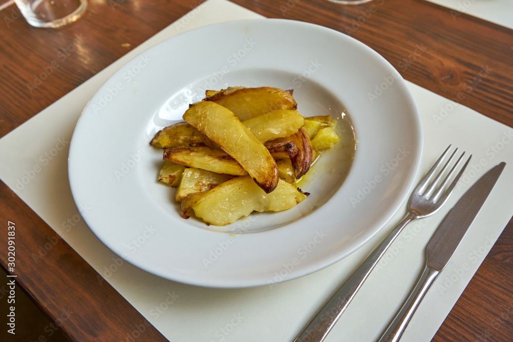 Roasted Potatoes Served On A Withe Plate On A Wooden Table. Roasted Potatoes Served On A Withe Plate On A Wooden Table.