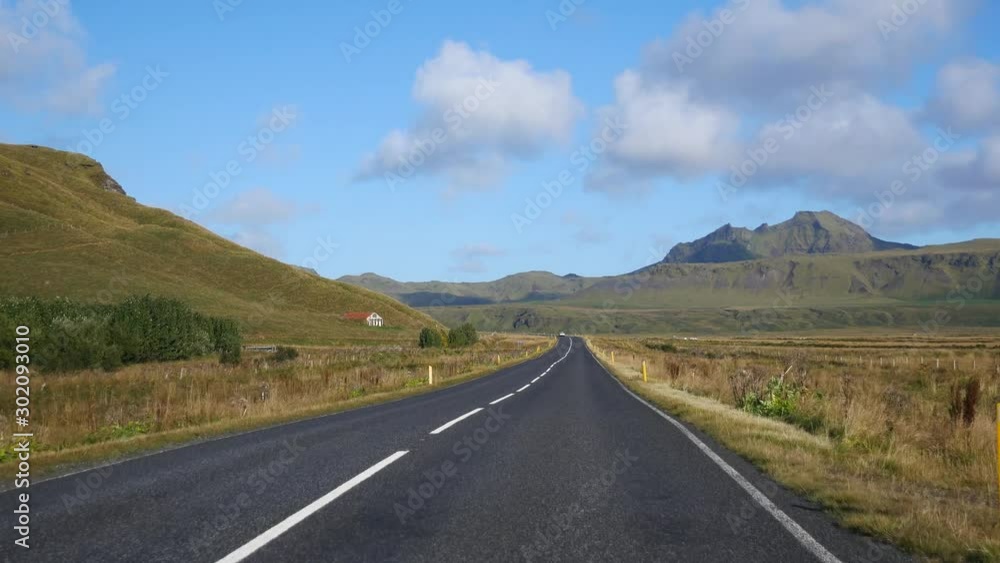 View inside the car through the windshield on beautiful countryside road with mountains landscape in Iceland