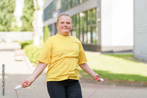 Cuadro en lienzo Happy overweight girl jumping with a rope outdoors