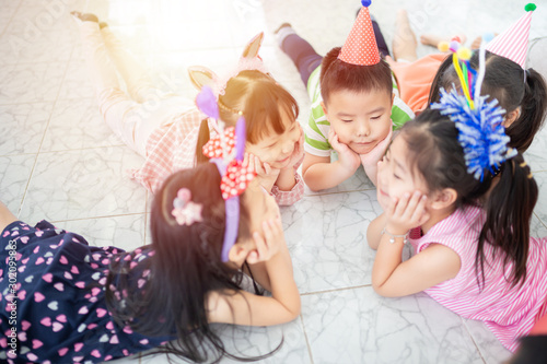 pretty asian children rest on floor, they rest chin on hand, they feeling happy and smile in recreation time, celebration party