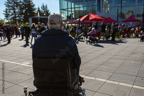 Selective focus on old man form the back sitting at open public space. People gathered for climate change protest and conference at background. photo