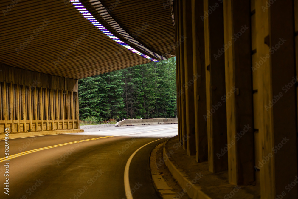 Curve tunnel for automobiles, exit at backgorund. Empty engineering construction with rhythm of lights and structure. Highway infraestructure. Curve tunnel for automobiles, exit at backgorund. Empty engineering construction with rhythm of lights and structure. Highway infraestructure.