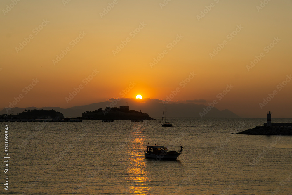 View of the coast of Kusadasi, Turkey. Sunset over the port in the tourist town. View of the coast of Kusadasi, Turkey. Sunset over the port in the tourist town.