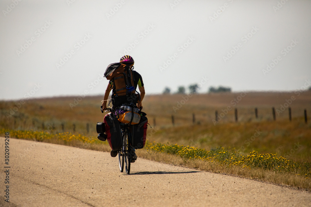 Man traveling on bicycle at countryside prepared with backpack and bike racks for his long journey. Natural rural environment in the background. Man traveling on bicycle at countryside prepared with backpack and bike racks for his long journey. Natural rural environment in the background.