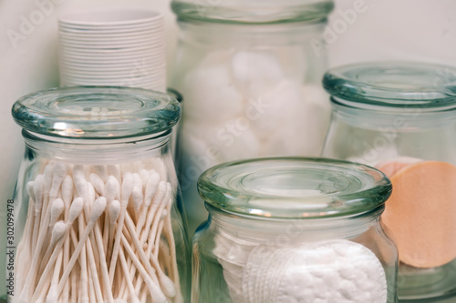 Sealed glass jars with makeup remover pads, cotton swabs and cotton balls for storage. photo