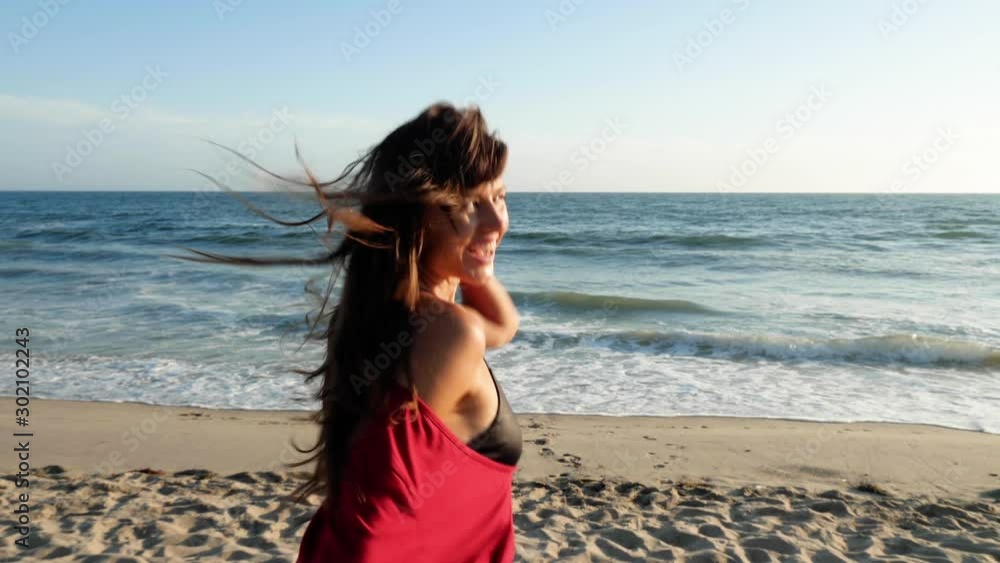 Attractive and playful woman running along the beach