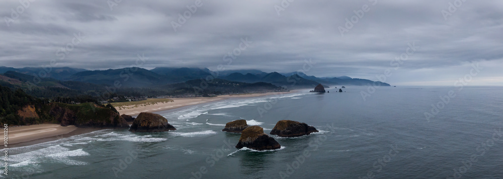 Cannon Beach, Oregon, United States. Beautiful Aerial Panoramic View of the Rocky Pacific Ocean Coast during a cloudy summer sunrise.