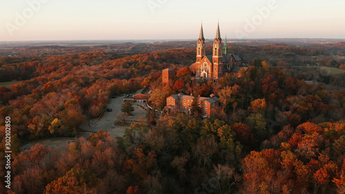 Aerial view of a church on the top of hill and autumn forest, red foliage . Fall season, autumn colors. Countryside, Wisconsin. Drone shots at sunset