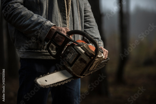 Lumberman work with chainsaw in the forest. Lifestyle work. Male hands with a saw in the woods. Detail .