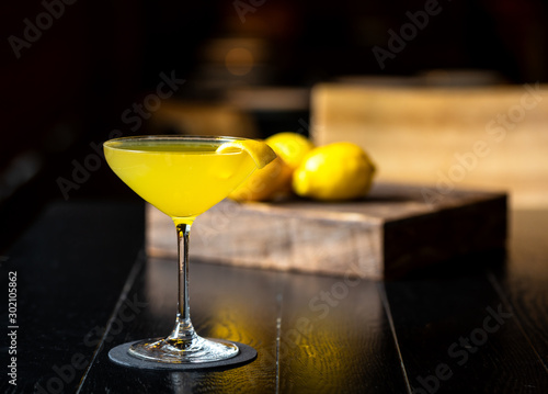 fresh yellow alcohol cocktail with lemon at a restaurant interior, dark background