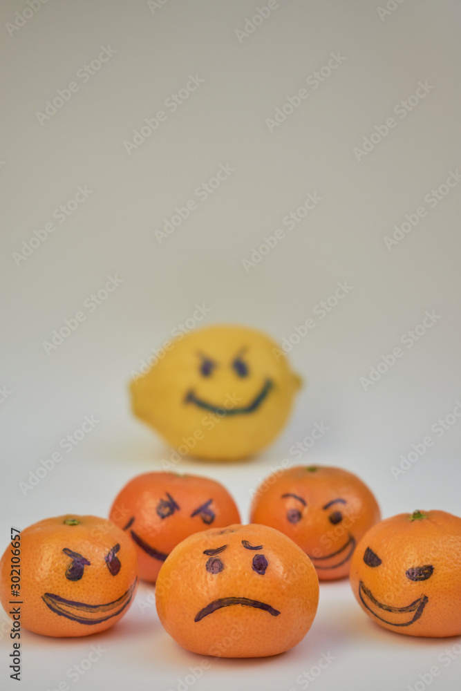 Concept of bullying, discrimination. Group of laughing emoticon faces and one alone look sad and depressed. Lemmons and mandarines. Cyber bullying on internet. Concept of bullying, discrimination. Group of laughing emoticon faces and one alone look sad and depressed. Lemmons and mandarines. Cyber bullying on internet.