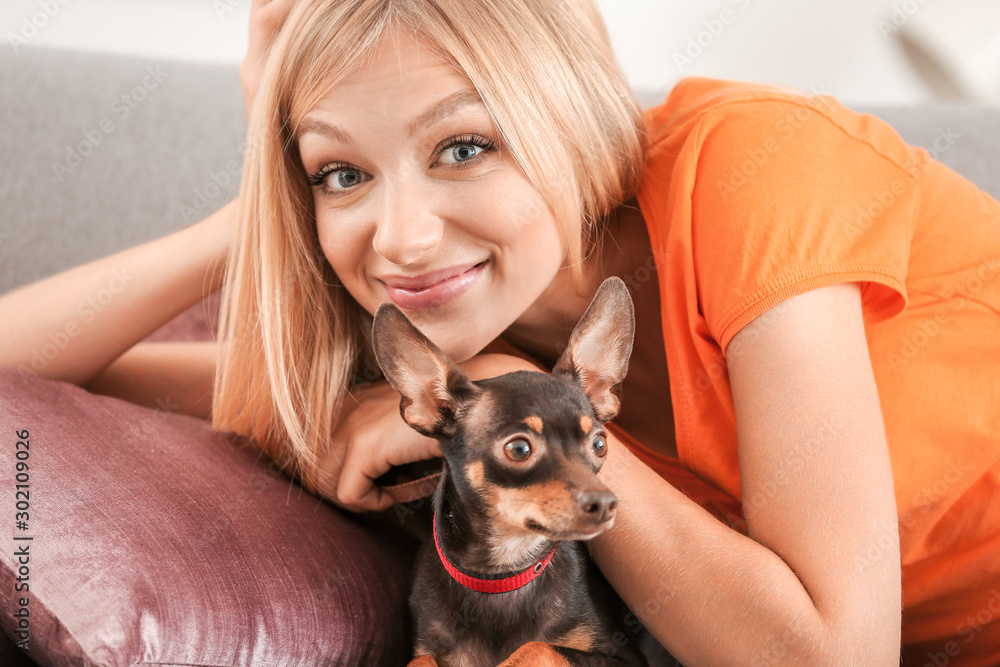 Beautiful young woman with cute toy terrier dog at home