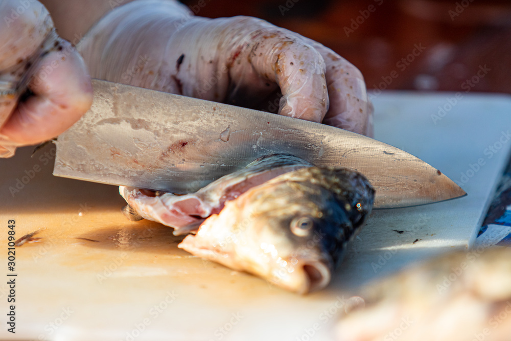 On the table, clean the fish from the scales and remove the entrails. Peeling and fillet of fresh fish that use a knife to clean the fish. Seafood cooking. On the table, clean the fish from the scales and remove the entrails. Peeling and fillet of fresh fish that use a knife to clean the fish. Seafood cooking.