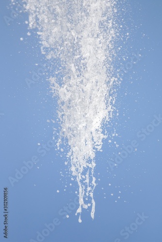Spray of water fountain against the blue sky. Water splashes are out of focus.