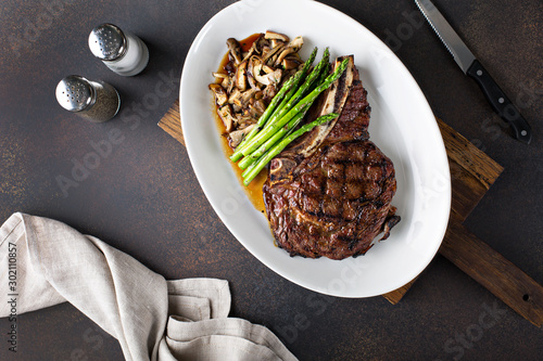 Bilde på lerret Bone-in ribeye beef steak with mushrooms and asparagus