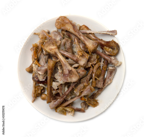 Chicken bones on a plate, after eating.