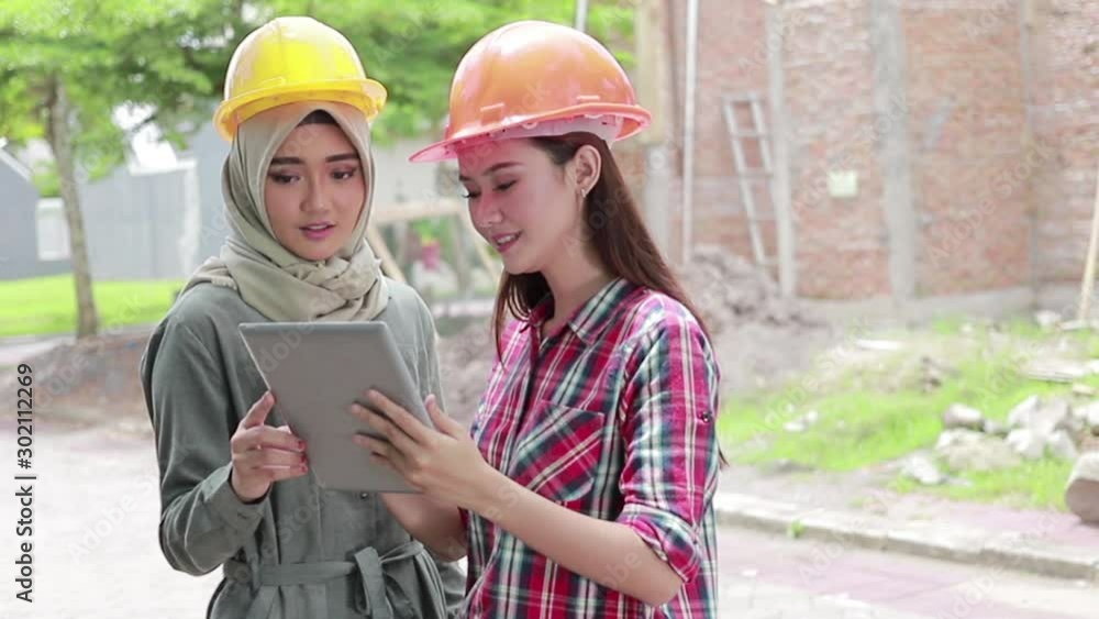 two female house designer or architect using tablet pc in front of the unfinished house two female house designer or architect using tablet pc in front of the unfinished house