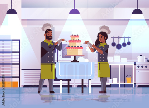 professional pastry chefs couple decorating tasty wedding cream cake african american woman man in uniform cooking food concept flat modern restaurant interior full length horizontal vector