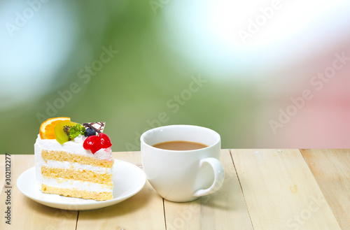 Slice cake with coffee cup on wood   green blur background