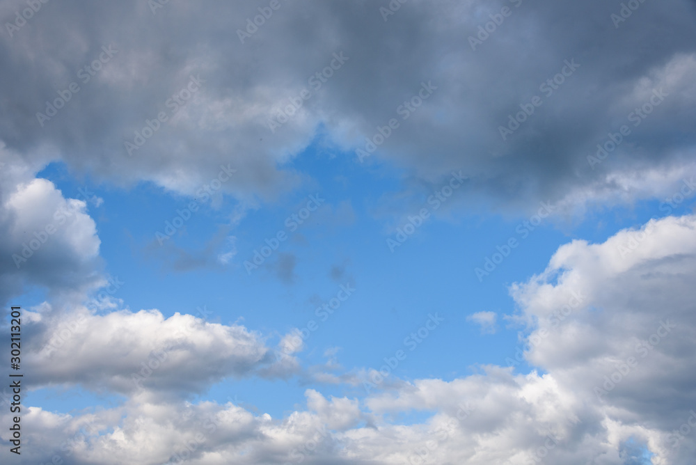 Nature background, blue sky framed by white and gray puffy clouds Nature background, blue sky framed by white and gray puffy clouds