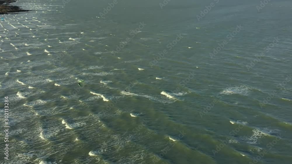 Kite surfer close to the beach, riding the wind with his kite, Drone footage. Aerial footage from high angle on a kite surfer. Kite surfer close to the beach, riding the wind with his kite, Drone footage. Aerial footage from high angle on a kite surfer.