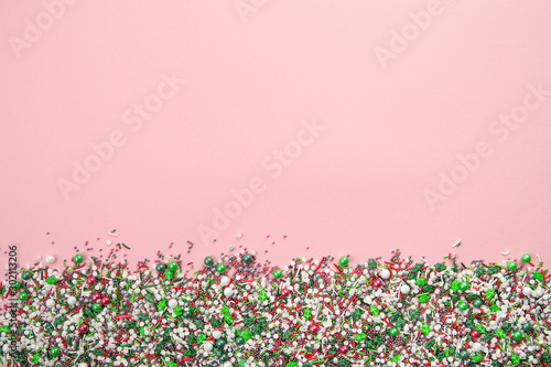 Colorful christmas sprinkles on edge of pink background