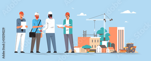 builders team shaking hands during meeting mix race engineers workers in helmet discussing new project on blueprint handshake agreement concept construction site background full length horizontal