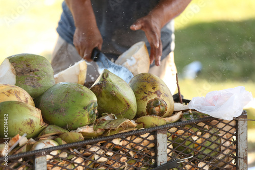 Man chopping green coconut with a machete